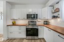 Well-appointed kitchen featuring white cabinetry, wood-tone countertops, stainless steel appliances, and a white subway tile backsplash - 33 4403 Riverbend Road, Edmonton, AB  - Indoor Photo Showing Kitchen 