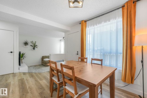 Dining area featuring wood flooring, a window with curtains, and an overhead light fixture - 33 4403 Riverbend Road, Edmonton, AB - Indoor Photo Showing Dining Room