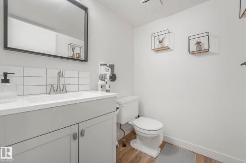 Bathroom featuring a vanity with a white countertop and light grey cabinetry, a mirror with a black frame, and a white toilet - 33 4403 Riverbend Road, Edmonton, AB - Indoor Photo Showing Bathroom