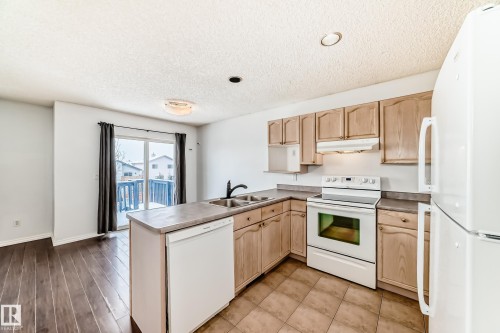 The kitchen features light wood cabinetry, white appliances, and a tiled floor - 1911 36 Avenue, Edmonton, AB - Indoor Photo Showing Kitchen With Double Sink
