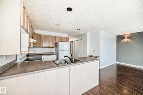 The kitchen features wood cabinetry, a double basin sink, and white appliances - 1911 36 Avenue, Edmonton, AB - Indoor Photo Showing Kitchen With Double Sink