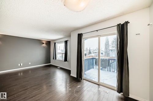 This room features dark wood flooring, a grey accent wall with wall sconces, and a window with dark curtains - 1911 36 Avenue, Edmonton, AB - Indoor Photo Showing Other Room