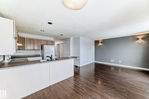 The kitchen features upper and lower cabinetry, a sink with a faucet, and a refrigerator - 1911 36 Avenue, Edmonton, AB - Indoor Photo Showing Kitchen