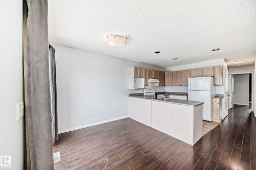 The property features an open concept kitchen and living area with dark wood flooring - 1911 36 Avenue, Edmonton, AB - Indoor Photo Showing Kitchen