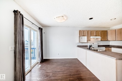 The kitchen features wooden cabinetry, a white stove, and a stainless steel sink - 1911 36 Avenue, Edmonton, AB - Indoor Photo Showing Kitchen