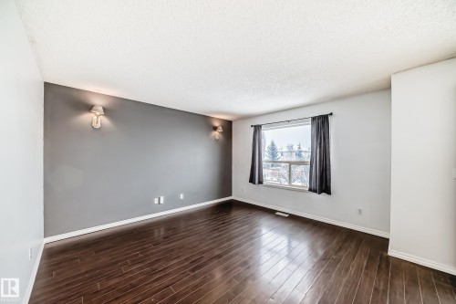 This room features rich, dark hardwood flooring and a neutral color palette with a prominent accent wall - 1911 36 Avenue, Edmonton, AB - Indoor Photo Showing Other Room