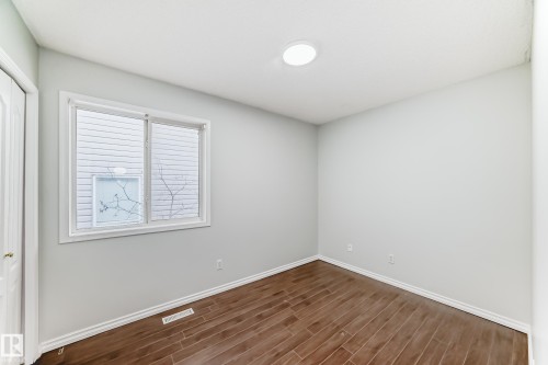 This room features durable plank flooring, a white trim, and a window providing natural light - 1911 36 Avenue, Edmonton, AB - Indoor Photo Showing Other Room