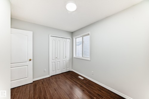 This room features rich wood flooring, a window providing natural light, and a closet with bi-fold doors - 1911 36 Avenue, Edmonton, AB - Indoor Photo Showing Other Room