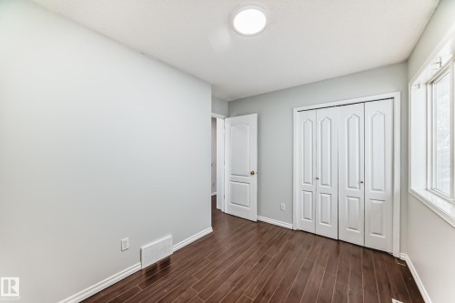 This room features rich wood flooring, a window providing natural light, and a white bi-fold closet door - 1911 36 Avenue, Edmonton, AB - Indoor Photo Showing Other Room