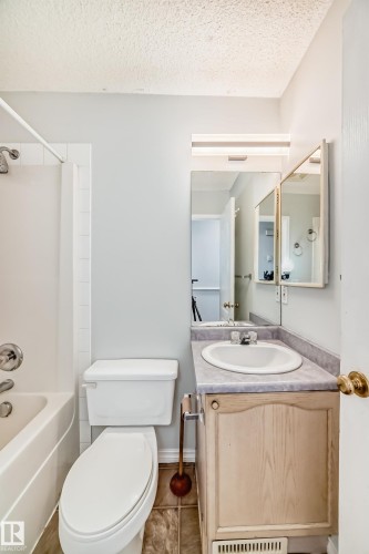 Bathroom featuring a bathtub, toilet, and a vanity with a sink and a mirror - 1911 36 Avenue, Edmonton, AB - Indoor Photo Showing Bathroom