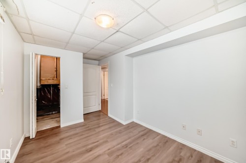 The room features light wood-look flooring, white walls, and a drop ceiling with recessed lighting - 1911 36 Avenue, Edmonton, AB - Indoor Photo Showing Other Room