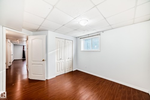 This room features rich hardwood flooring, a window providing natural light, white walls, and a white ceiling - 1911 36 Avenue, Edmonton, AB - Indoor Photo Showing Other Room