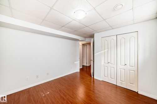 This room features rich brown flooring, white walls, and a white drop ceiling - 1911 36 Avenue, Edmonton, AB - Indoor Photo Showing Other Room