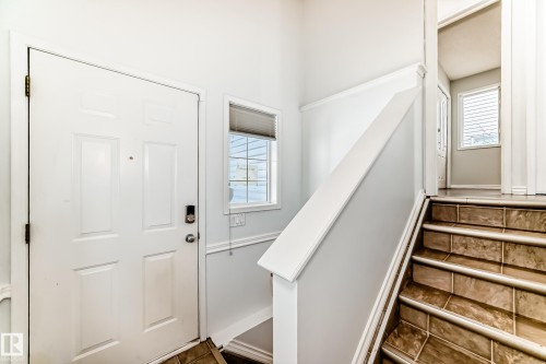 Entryway featuring a white paneled door with a smart lock, a window with blinds, and tiled stairs with white trim - 1911 36 Avenue, Edmonton, AB - Indoor Photo Showing Other Room