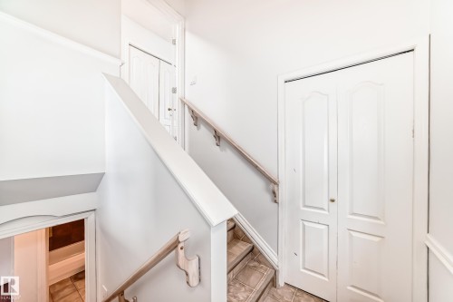 Interior staircase with light-toned handrails, tiled steps, and white bi-fold doors - 1911 36 Avenue, Edmonton, AB - Indoor Photo Showing Other Room