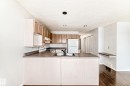 The kitchen features light wood cabinetry, a white refrigerator, and a dark countertop - 1911 36 Avenue, Edmonton, AB  - Indoor Photo Showing Kitchen 