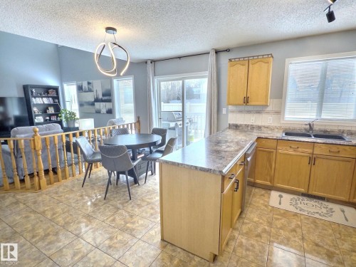 The kitchen features wood cabinetry, a double basin sink, and an island with a countertop - 14 6608 158 Avenue, Edmonton, AB - Indoor