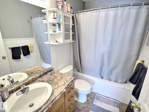 Bathroom featuring a vanity with a countertop, an integrated sink, and a mirror - 14 6608 158 Avenue, Edmonton, AB - Indoor Photo Showing Bathroom