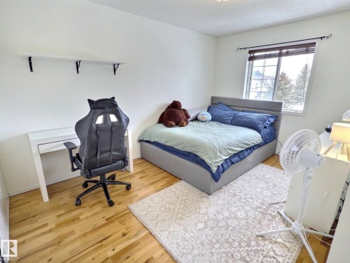This room features hardwood floors, white walls, and a window providing natural light - 14 6608 158 Avenue, Edmonton, AB - Indoor Photo Showing Bedroom