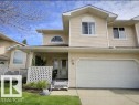 The property features a light-colored exterior with a front-facing garage door, a covered entrance, and a well-maintained lawn area - 14 6608 158 Avenue, Edmonton, AB  - Outdoor With Deck Patio Veranda 