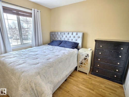 Bedroom featuring hardwood floors, a window with curtains, and a neutral wall color - 14 6608 158 Avenue, Edmonton, AB - Indoor Photo Showing Bedroom
