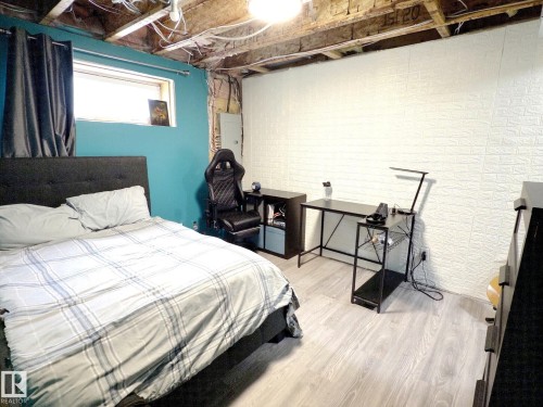 This interior space features light-colored flooring, a window with dark curtains, and a dark upholstered bed frame - 14 6608 158 Avenue, Edmonton, AB - Indoor Photo Showing Other Room