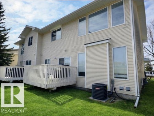 The property features light-colored siding, a well-maintained lawn, and two outdoor decks with white railings - 14 6608 158 Avenue, Edmonton, AB - Outdoor With Deck Patio Veranda With Exterior