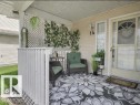 Inviting covered porch with a patterned rug, a privacy lattice, and a decorative front door with a heart-shaped window - 14 6608 158 Avenue, Edmonton, AB  - Outdoor With Deck Patio Veranda With Exterior 