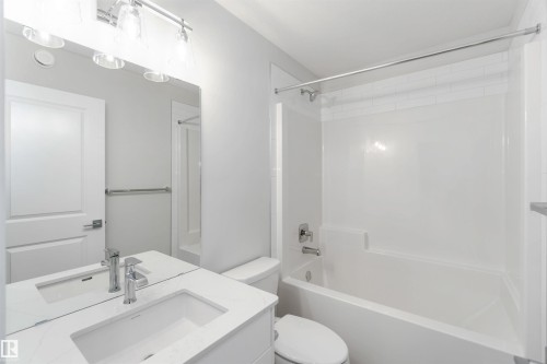 Bathroom featuring a vanity with an integrated sink, a toilet, and a bathtub with a shower - 18940 28 Avenue, Edmonton, AB - Indoor Photo Showing Bathroom