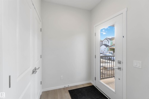 The entry features light-toned flooring and a white door with a glass panel, offering views of the surrounding neighborhood - 18940 28 Avenue, Edmonton, AB - Indoor Photo Showing Other Room