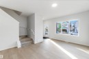 The property features a bright living area with light wood-style flooring, a large window providing natural light, and a staircase with carpeted treads - 18940 28 Avenue, Edmonton, AB  - Indoor Photo Showing Other Room 
