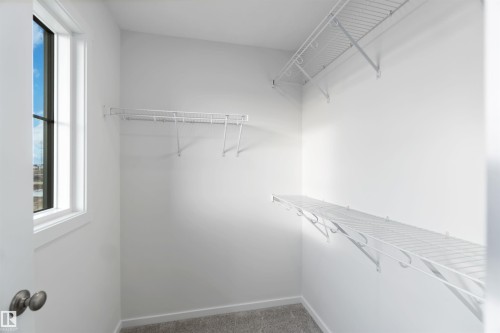 This closet features a window providing natural light, wire shelving, and wire hanging rods - 5452 Hawthorn Run, Edmonton, AB - Indoor With Storage