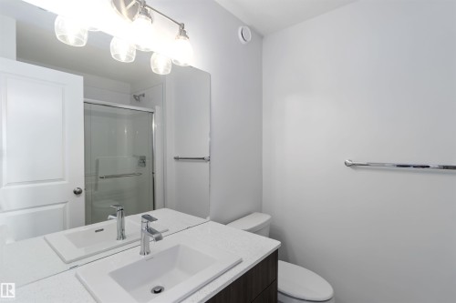 Bathroom featuring a vanity with an undermount sink, a chrome faucet, and a large mirror with overhead lighting - 5452 Hawthorn Run, Edmonton, AB - Indoor Photo Showing Bathroom