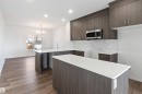 Kitchen featuring dark wood cabinetry, light countertops, a stainless steel microwave, and white tiled backsplash - 5452 Hawthorn Run, Edmonton, AB  - Indoor Photo Showing Kitchen With Upgraded Kitchen 
