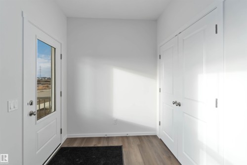 This entryway features light-toned flooring, a white door with a window, and a pair of white closet doors with silver hardware - 5452 Hawthorn Run, Edmonton, AB - Indoor Photo Showing Other Room