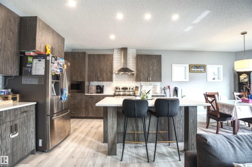 The kitchen features modern wood-grain cabinetry, stainless steel appliances, a white subway tile backsplash, and recessed lighting - 20503 99 Avenue, Edmonton, AB - Indoor Photo Showing Kitchen With Upgraded Kitchen
