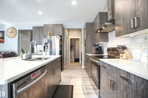 The kitchen features extensive cabinetry with brushed nickel hardware, stainless steel appliances, and light-colored countertops - 20503 99 Avenue, Edmonton, AB - Indoor Photo Showing Kitchen With Double Sink With Upgraded Kitchen