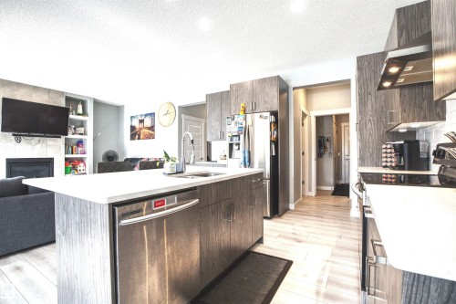 Open concept living area with a kitchen island featuring a sink and stainless steel dishwasher - 20503 99 Avenue, Edmonton, AB - Indoor Photo Showing Kitchen With Double Sink