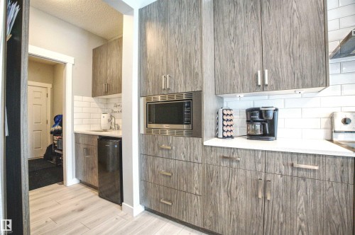 Kitchenette featuring light wood grain cabinetry, a built-in microwave, white subway tile backsplash, and a sink with a stainless steel faucet - 20503 99 Avenue, Edmonton, AB - Indoor Photo Showing Other Room