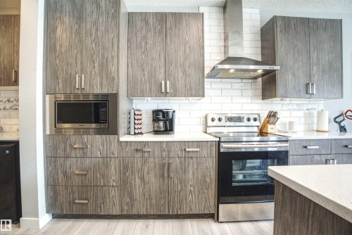 Kitchen featuring grey wood grain cabinetry, white subway tile backsplash, stainless steel appliances, and light-colored countertops - 20503 99 Avenue, Edmonton, AB - Indoor Photo Showing Kitchen
