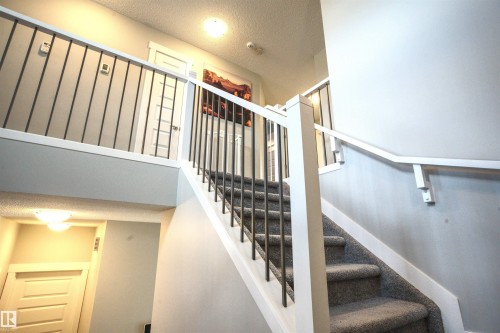 Staircase featuring carpeted stairs, a white handrail, and a contemporary metal railing - 20503 99 Avenue, Edmonton, AB - Indoor Photo Showing Other Room