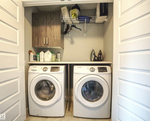 Convenient laundry area featuring a washer, a dryer, a storage cabinet, and a wire shelf - 20503 99 Avenue, Edmonton, AB - Indoor Photo Showing Laundry Room