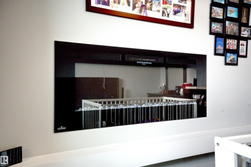 Modern wall-mounted fireplace with a black glass front - 20503 99 Avenue, Edmonton, AB - Indoor Photo Showing Other Room