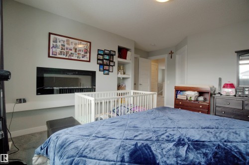Bedroom featuring a built-in electric fireplace and shelving, with carpeted flooring - 20503 99 Avenue, Edmonton, AB - Indoor Photo Showing Bedroom