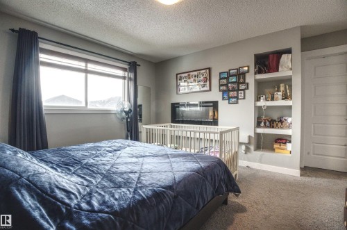 This room features carpeted flooring, a window with blinds and curtains, and built-in shelving - 20503 99 Avenue, Edmonton, AB - Indoor Photo Showing Bedroom