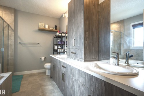 Bathroom featuring a double vanity with ample storage, a shower with a clear glass enclosure, and a built-in bathtub with tiled surrounds - 20503 99 Avenue, Edmonton, AB - Indoor Photo Showing Bathroom