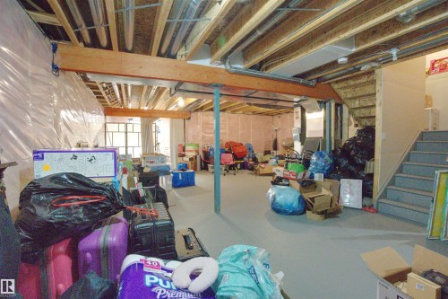 The property features an unfinished basement with exposed ceiling joists and support beams, a staircase, and a window providing natural light - 20503 99 Avenue, Edmonton, AB - Indoor Photo Showing Basement