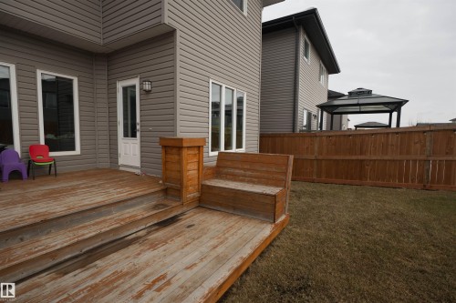 The property features an outdoor wooden deck with built-in seating, a door leading indoors, and a fenced yard with a gazebo - 20503 99 Avenue, Edmonton, AB - Outdoor With Exterior