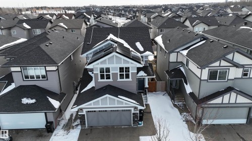 Exterior view of the property featuring a two-car garage, solar panels on the roof, and a snow-covered driveway - 20503 99 Avenue, Edmonton, AB - Outdoor With Facade