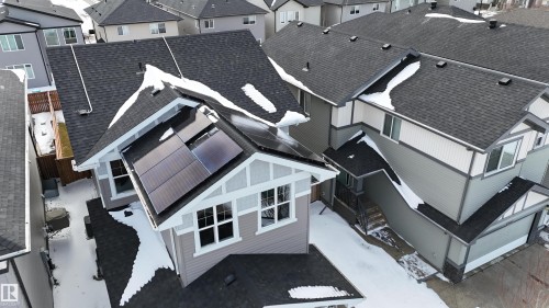 The property features a dark shingled roof with visible solar panels, light-colored siding, and white trim around the windows - 20503 99 Avenue, Edmonton, AB - Outdoor